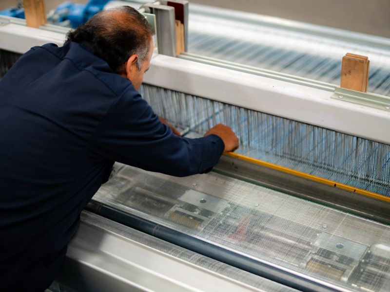 Técnico de Comenk inspeccionando el proceso de tejido de malla de alambre en la planta de manufactura.