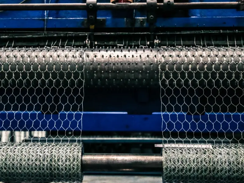 Máquina tejedora industrial produciendo rollos de malla de alambre hexagonal en la planta de manufactura de Comenk.
